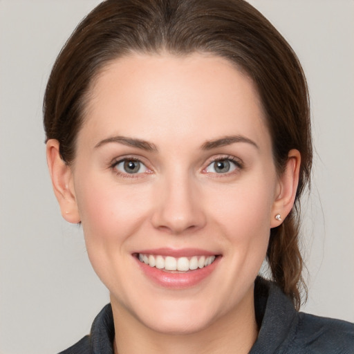 Joyful white young-adult female with medium  brown hair and grey eyes