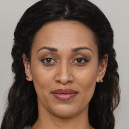 Joyful black adult female with long  brown hair and brown eyes