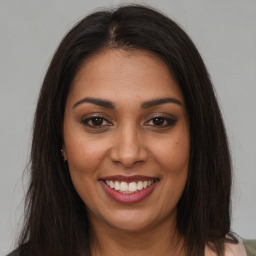 Joyful black young-adult female with long  brown hair and brown eyes