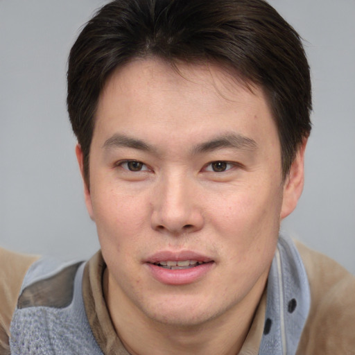 Joyful asian young-adult male with short  brown hair and brown eyes