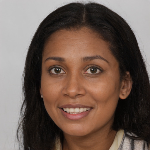 Joyful black young-adult female with long  brown hair and brown eyes