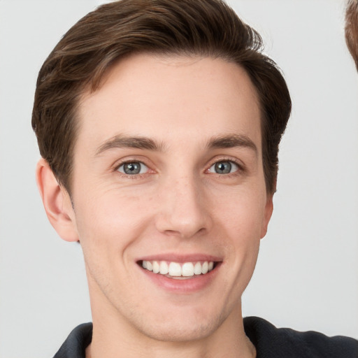 Joyful white young-adult male with short  brown hair and grey eyes