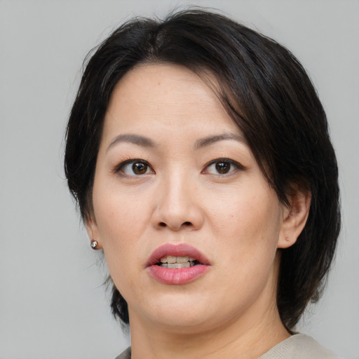 Joyful asian adult female with medium  brown hair and brown eyes