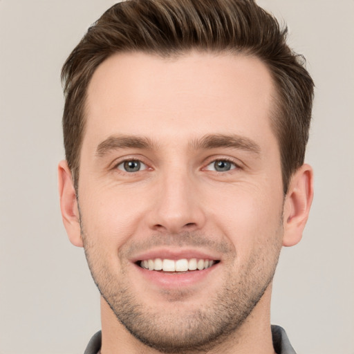 Joyful white young-adult male with short  brown hair and grey eyes