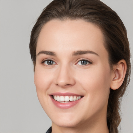 Joyful white young-adult female with medium  brown hair and grey eyes