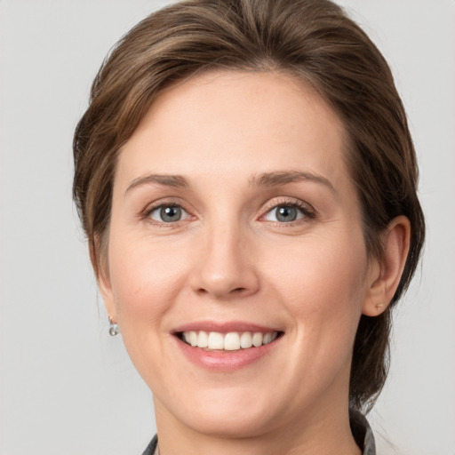 Joyful white young-adult female with medium  brown hair and grey eyes