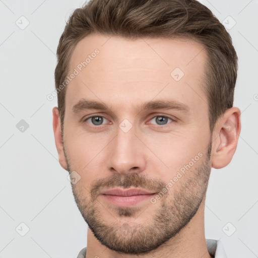 Joyful white young-adult male with short  brown hair and grey eyes