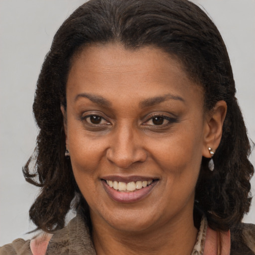 Joyful black adult female with long  brown hair and brown eyes