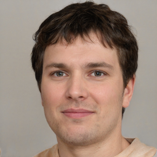 Joyful white young-adult male with short  brown hair and grey eyes