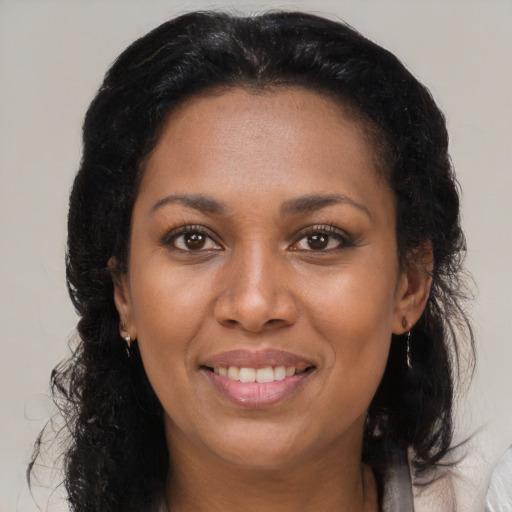 Joyful black adult female with long  brown hair and brown eyes