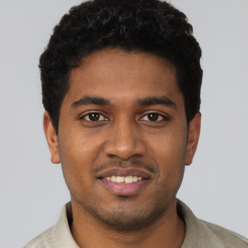 Joyful black young-adult male with short  brown hair and brown eyes