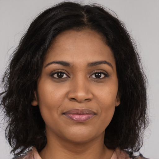 Joyful black young-adult female with long  brown hair and brown eyes
