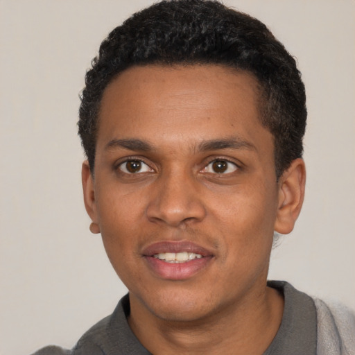 Joyful black young-adult male with short  black hair and brown eyes
