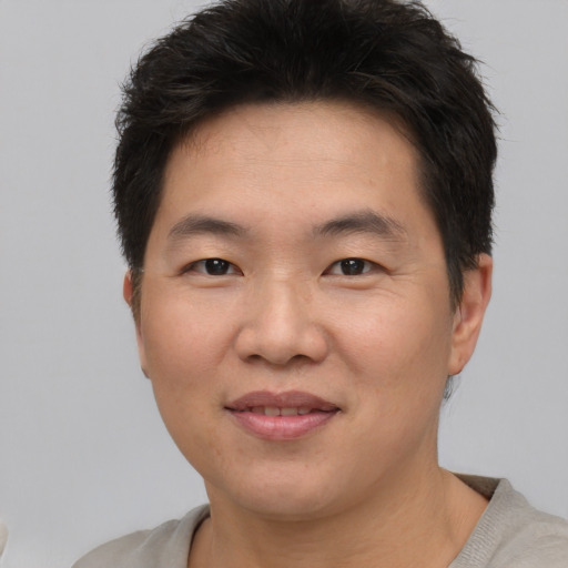 Joyful asian young-adult male with short  brown hair and brown eyes