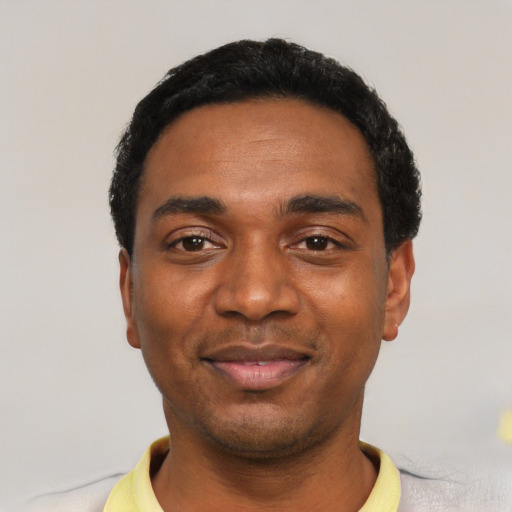 Joyful black young-adult male with short  black hair and brown eyes