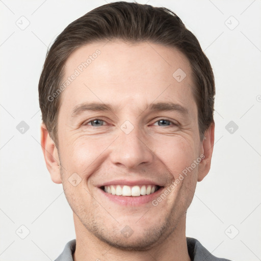 Joyful white young-adult male with short  brown hair and grey eyes