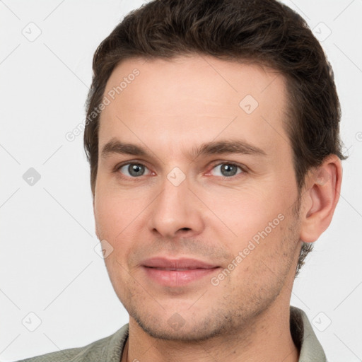 Joyful white young-adult male with short  brown hair and grey eyes