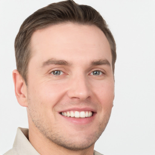 Joyful white young-adult male with short  brown hair and grey eyes