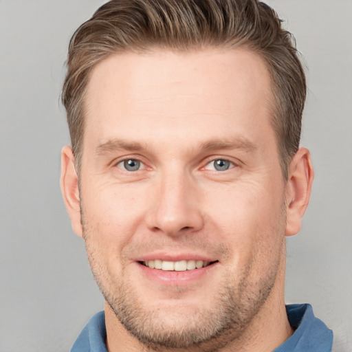 Joyful white young-adult male with short  brown hair and grey eyes