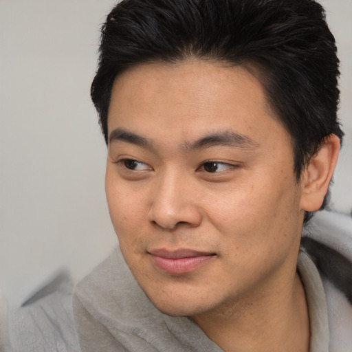 Joyful asian young-adult male with short  brown hair and brown eyes