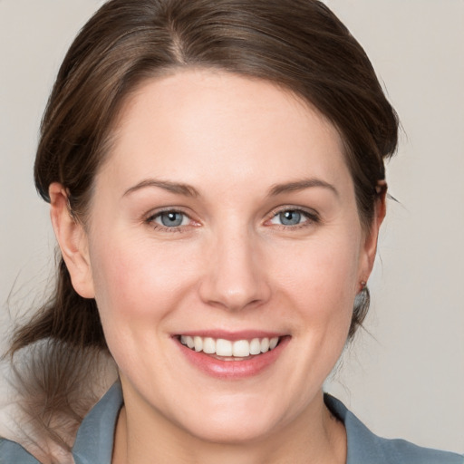 Joyful white young-adult female with medium  brown hair and grey eyes