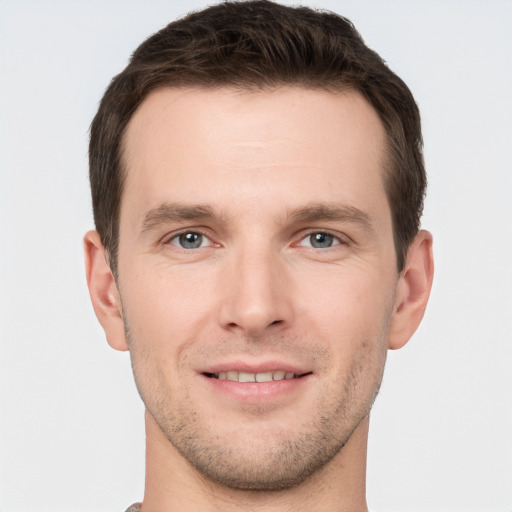 Joyful white young-adult male with short  brown hair and grey eyes