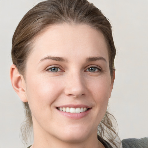 Joyful white young-adult female with medium  brown hair and grey eyes