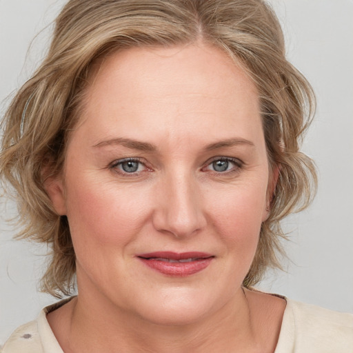 Joyful white adult female with medium  brown hair and blue eyes