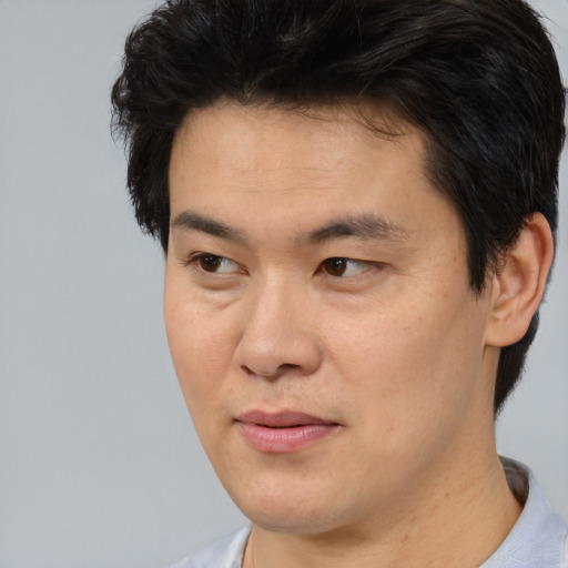 Joyful asian adult male with short  brown hair and brown eyes