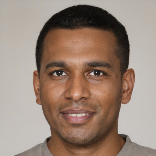 Joyful black young-adult male with short  black hair and brown eyes