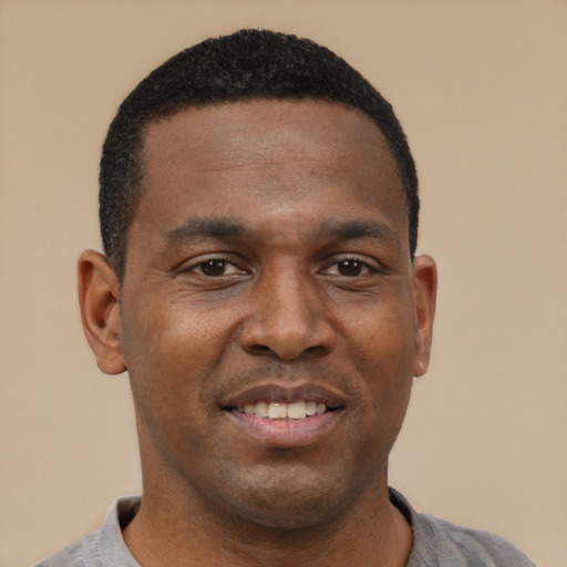Joyful black young-adult male with short  black hair and brown eyes