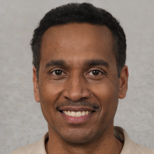 Joyful black adult male with short  black hair and brown eyes