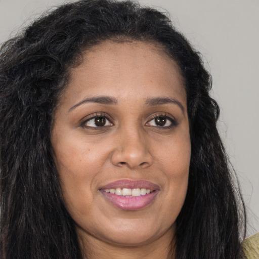 Joyful black young-adult female with long  brown hair and brown eyes