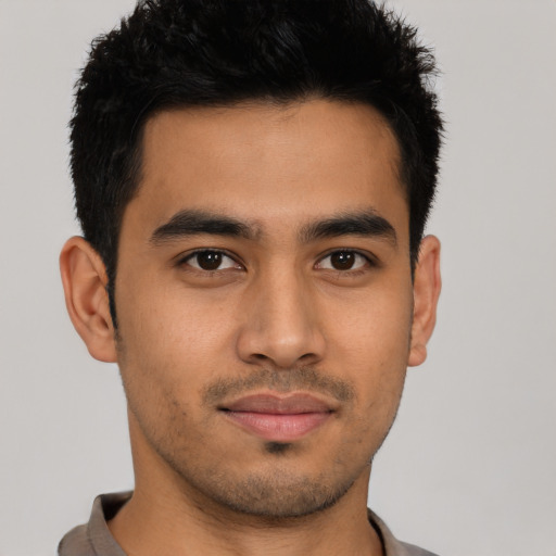 Joyful latino young-adult male with short  brown hair and brown eyes