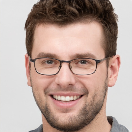 Joyful white young-adult male with short  brown hair and grey eyes