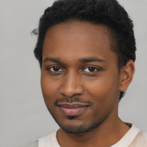 Joyful black young-adult male with short  brown hair and brown eyes