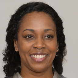 Joyful black adult female with long  brown hair and brown eyes