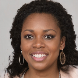 Joyful black young-adult female with long  brown hair and brown eyes