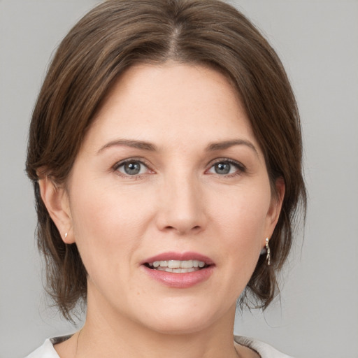 Joyful white young-adult female with medium  brown hair and grey eyes