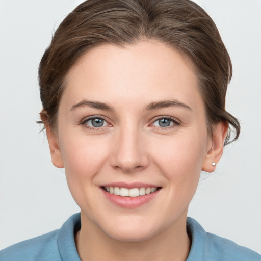 Joyful white young-adult female with medium  brown hair and grey eyes