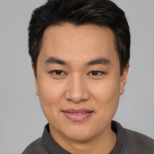 Joyful asian adult male with short  brown hair and brown eyes