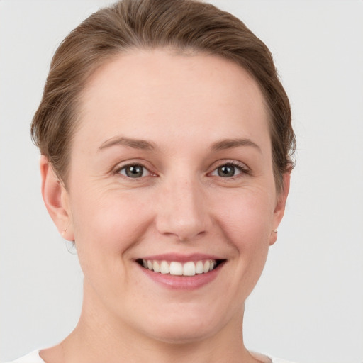 Joyful white young-adult female with short  brown hair and grey eyes