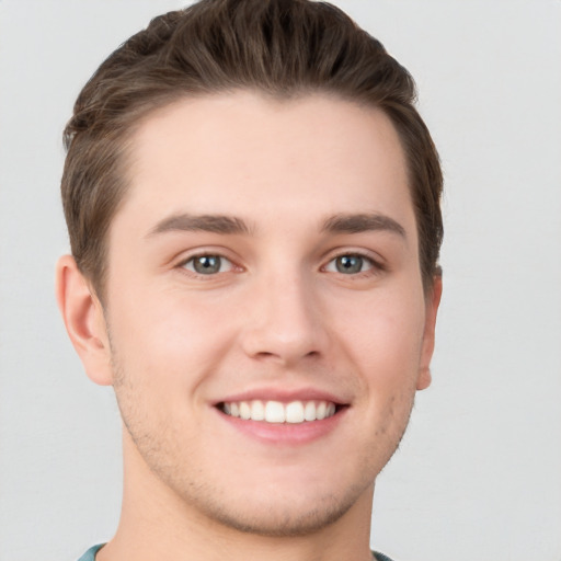 Joyful white young-adult male with short  brown hair and grey eyes