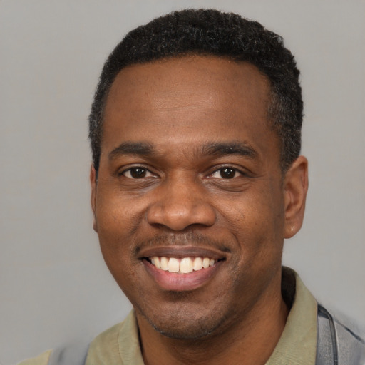Joyful black young-adult male with short  black hair and brown eyes
