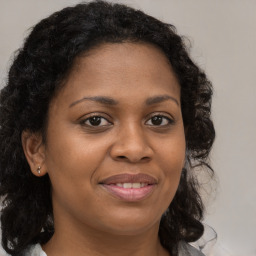 Joyful black young-adult female with long  brown hair and brown eyes