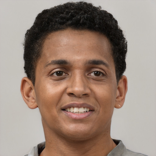 Joyful black young-adult male with short  brown hair and brown eyes