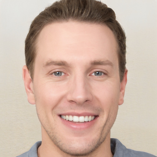 Joyful white young-adult male with short  brown hair and grey eyes