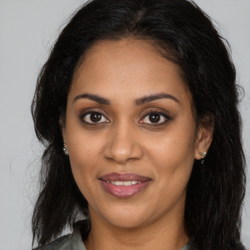 Joyful black young-adult female with long  brown hair and brown eyes