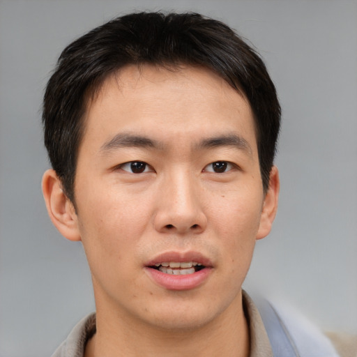 Joyful asian young-adult male with short  brown hair and brown eyes