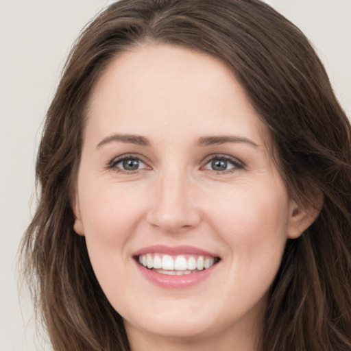 Joyful white young-adult female with long  brown hair and grey eyes